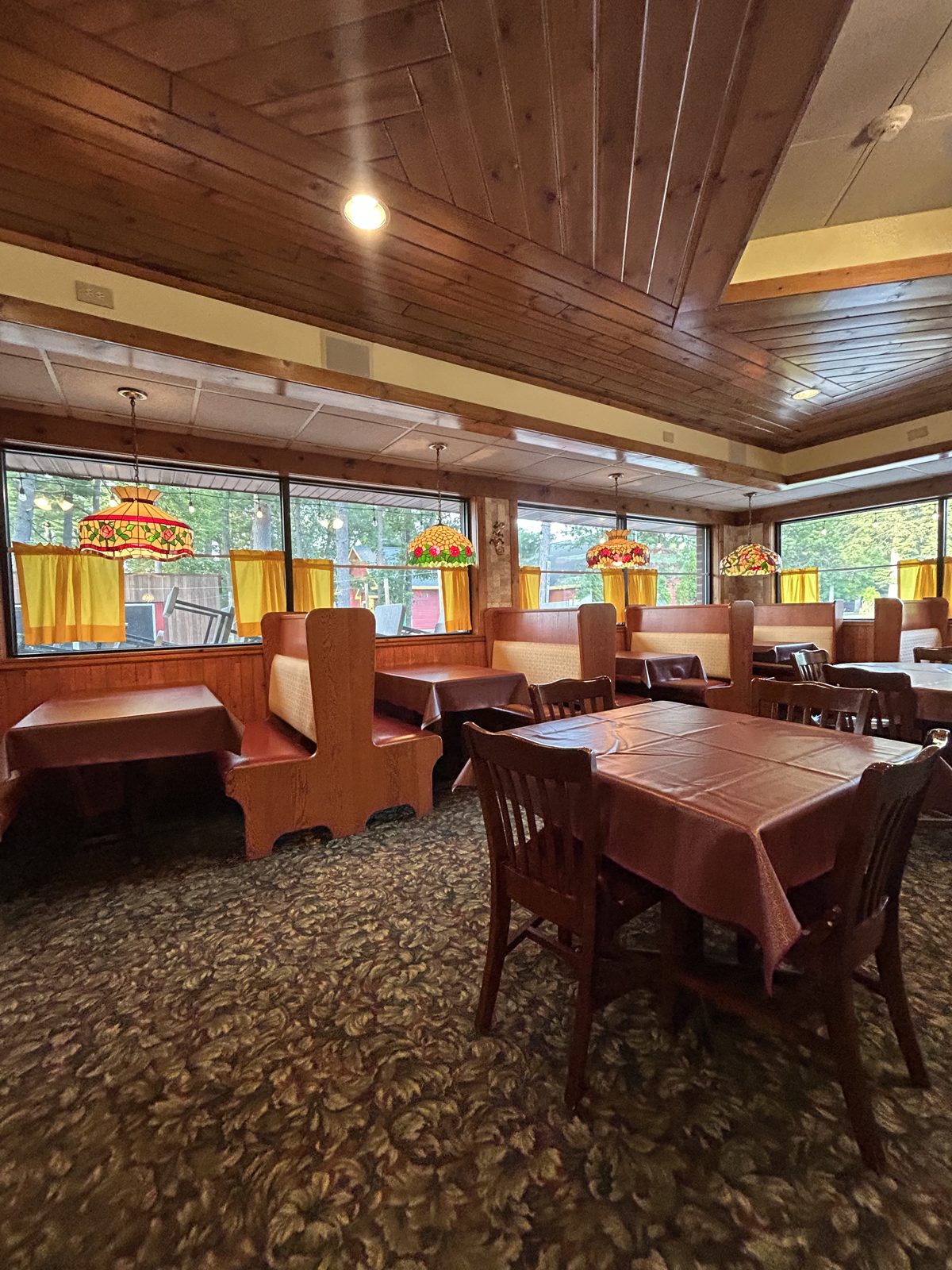 Inside the Chicken Shack dining room in Waupaca, WI with wood booths and stained-glass lamps